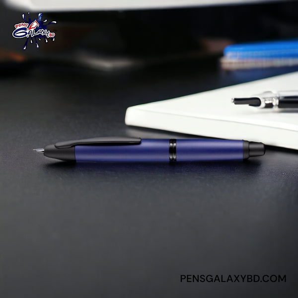 Pilot Vanishing Point Fountain Pen - Matte Blue - On a black desk beside a diary